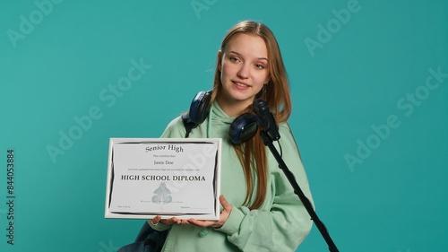 Fotografie Proud teenage student holding high school diploma, using microphone to thank teachers, studio backdrop