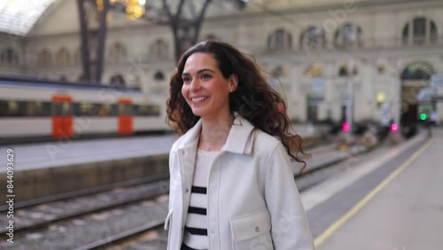 Happy young traveler woman with luggage walking at platform train station. Travel and transportation concept.