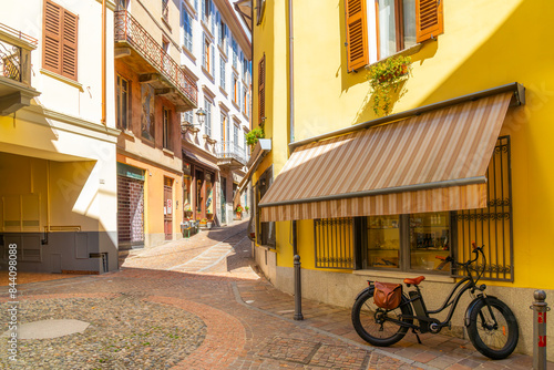 Fototapeta Naklejka Na Ścianę i Meble -  A bicycle is parked on a colorful shopping street in the historic and colorful center of the lakefront village of Menaggio, Italy, on the shores of Lake Como.