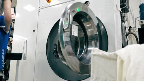 professional dry cleaning young girl throws a blue jacket into professional washing machine