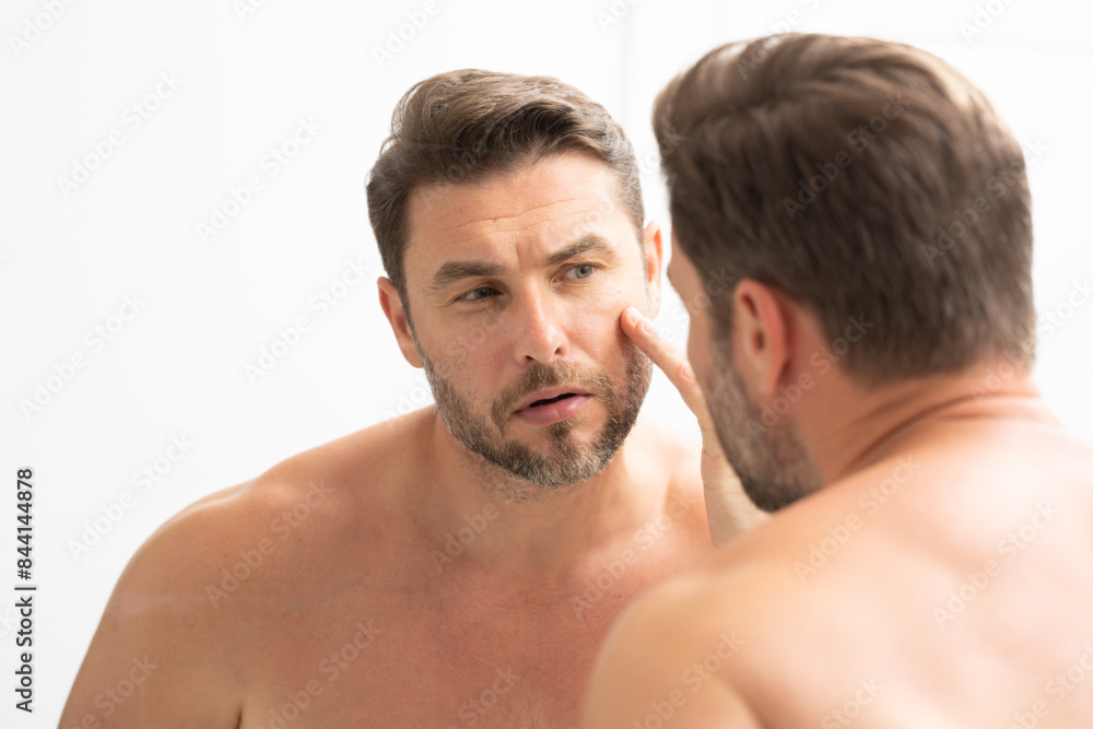 a man in a bathrobe in the bathroom looking at his wrinkles and pimples on his face. A man is looking at his reflection in a mirror. A man is looking at his reflection in a mirror. a man in a bathrobe in the bathroom looking at his wrinkles and pimples on his face. A man is looking at his reflection in a mirror. A man is looking at his reflection in a mirror.
