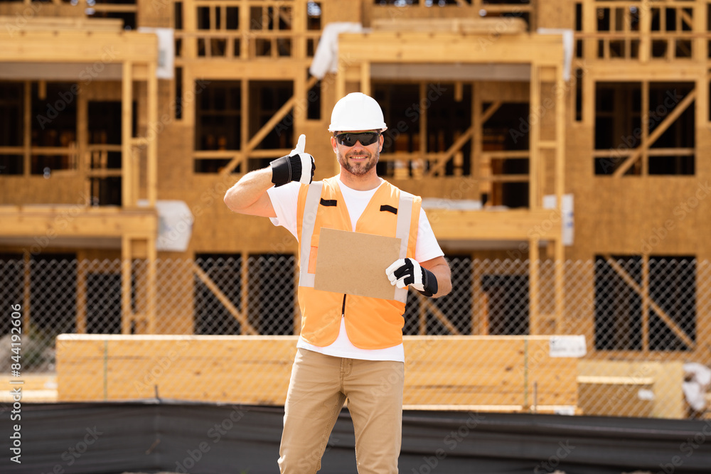Man Contractor holds piece of empty cardboard sign in his hands. a male construction worker in a helmet stands in a construction zone with empty cardboard. Construction Worker on Duty Man Contractor holds piece of empty cardboard sign in his hands. a male construction worker in a helmet stands in a construction zone with empty cardboard. Construction Worker on Duty