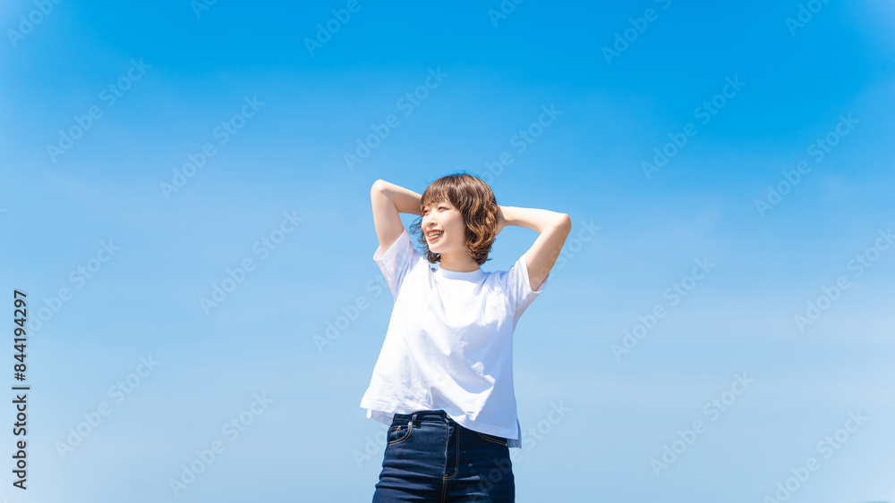 夏の青空と白いTシャツを着た笑顔の女性