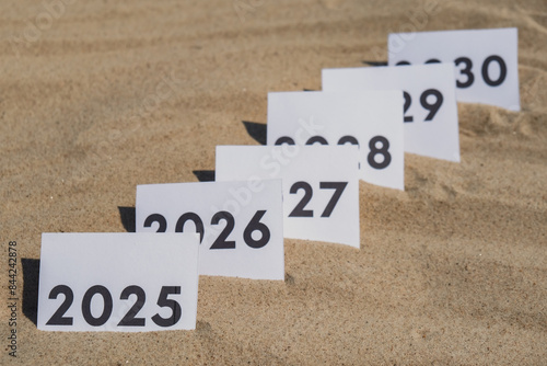 Paper cards with numbers of years from 2024 to 2030 in a row. New year start concept. Resolution time is flying plan goal motivation countdown photo