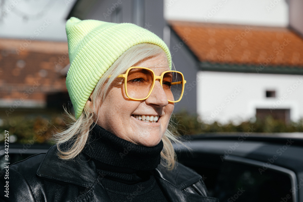 Smiling older woman wearing yellow glasses and green beanie, outdoors Smiling older woman wearing yellow glasses and green beanie, outdoors