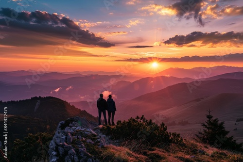 A romantic scene as a couple stands overlooking a stunning mountainous landscape at sunset