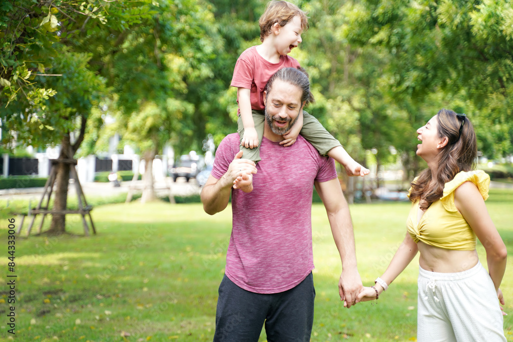 Fototapeta premium Happy family picnic and plying football in the park public on summer holiday. Family relax and enjoying outdoor. Family and Lifestyle Concept