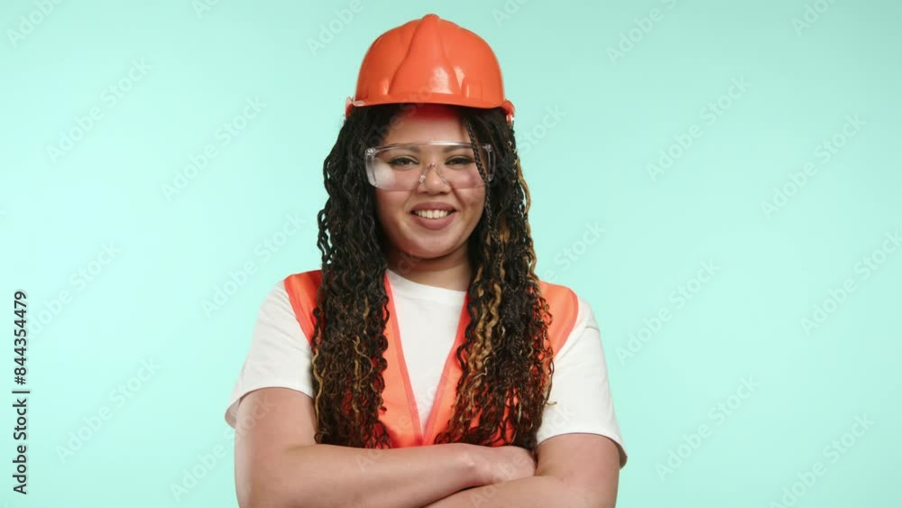 A confident female construction worker, smiling and wearing safety gear, poses against a light aqua background. She projects professionalism and expertise in the construction industry A confident female construction worker, smiling and wearing safety gear, poses against a light aqua background. She projects professionalism and expertise in the construction industry