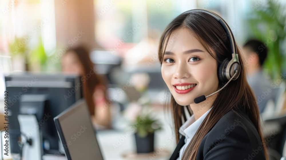 Attractive Asian businesswoman in suit and headset smiling while working on computer at office Customer service assistant working in office. VOIP Helpdesk headset Attractive Asian businesswoman in suit and headset smiling while working on computer at office Customer service assistant working in office. VOIP Helpdesk headset