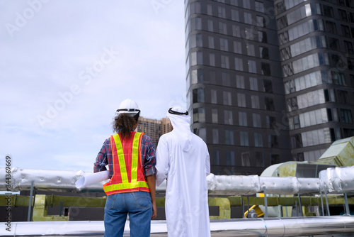 Middle eastern man and African woman are working together on rooftop. © Suney