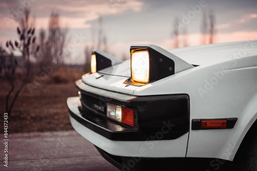 White old japanese 1980s car with pop-up headlights. Blurry countryside in the background photo