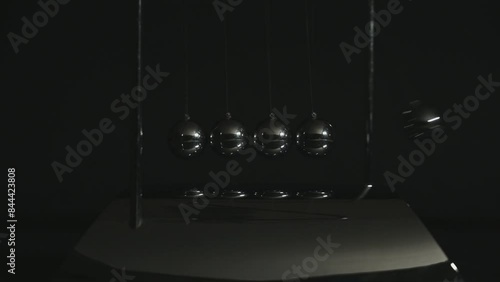 Newton cradle balancing balls in a dark tone. movement physics and common physical laws concept for action and reaction, cause and effect. Balls Newton.
