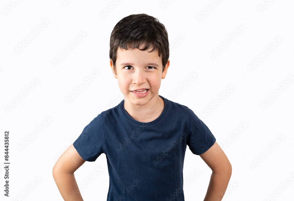 Little boy in white shirt looking at camera with angry expression. he is arms akimbo while standing against white background Little boy in white shirt looking at camera with angry expression. he is arms akimbo while standing against white background
