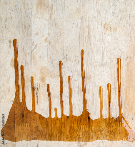 A wooden surface with streaks of varnish or stain dripping down. The wood grain is clearly visible, and the drips create an artistic, dynamic effect.