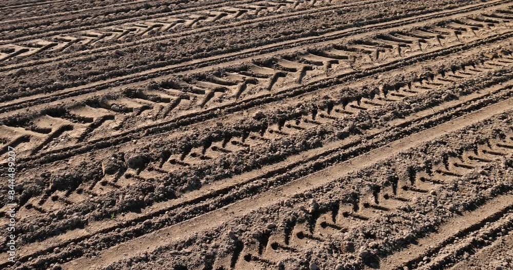 a plowed agricultural field with traces of a tractor, the soil on the field during sowing with traces of agricultural machinery a plowed agricultural field with traces of a tractor, the soil on the field during sowing with traces of agricultural machinery