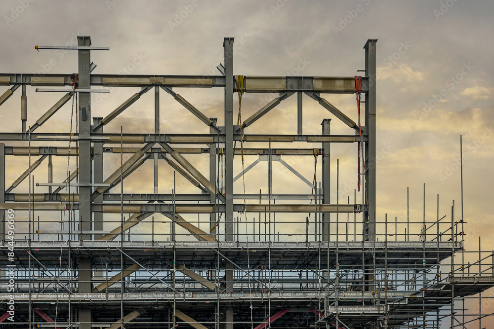 Construction site with cranes on orange sunset, sunrise sky background. Steel frame structure, structural steel beam build large buildings at construction site . construction machinery. Construction site with cranes on orange sunset, sunrise sky background. Steel frame structure, structural steel beam build large buildings at construction site . construction machinery.