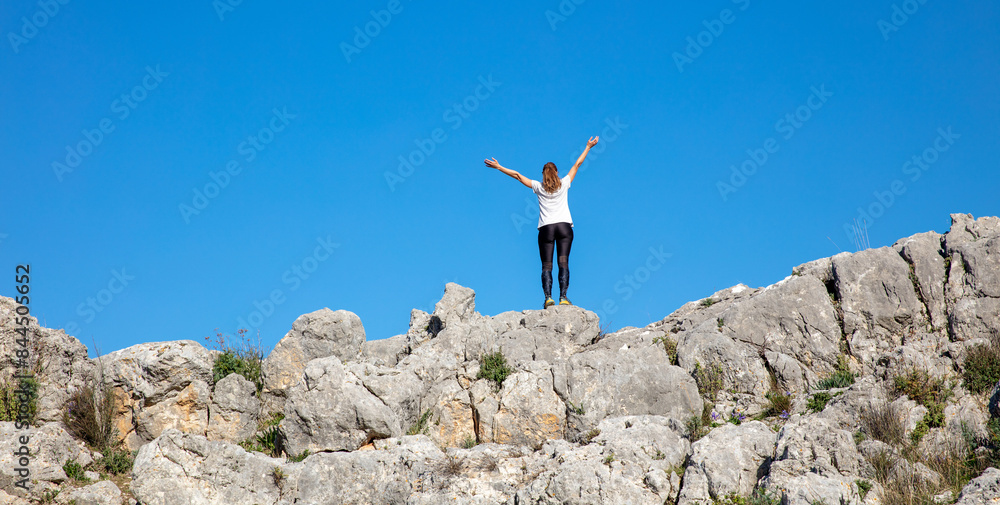 Happy hiker woman on cliff with arms raised and bue sky Happy hiker woman on cliff with arms raised and bue sky
