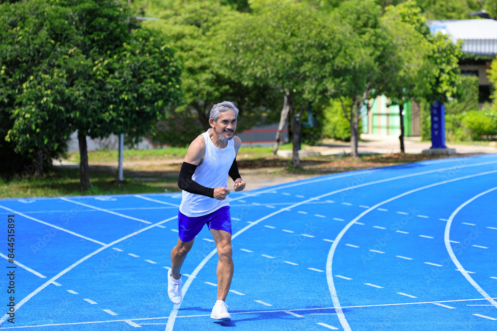 Obraz premium Senior Asian athlete is practicing running in the professional blue track for professional exercise, sport training workout and healthy for longevity