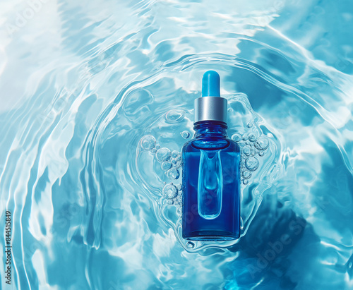 Blue cosmetic jar with facial serum on a background of blue water