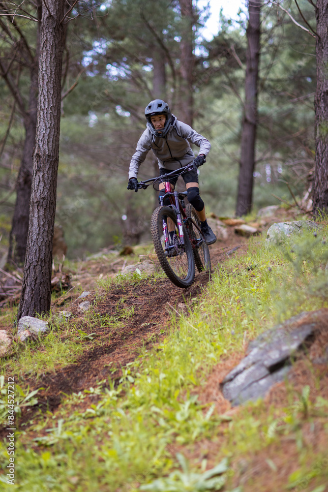 teen boy riding a mountain bike downhill through pine forest teen boy riding a mountain bike downhill through pine forest