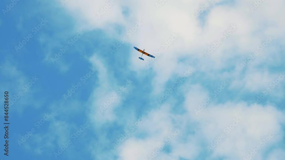 Radio Controlled Glider. Small Airplane Gliding Serenely in a Vivid Blue Sky with Cloud Formations Radio Controlled Glider. Small Airplane Gliding Serenely in a Vivid Blue Sky with Cloud Formations