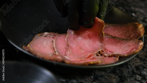 Chef with tongs puts meat on pizza from a plate slow motion close-up