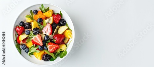Summer salad with fruit in a white bowl against a white backdrop