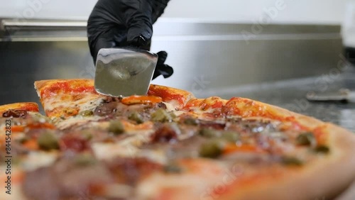Chef with tongs takes ready hot pizza stretches cheese slow motion
