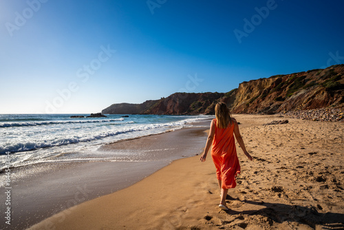 Beautiful woman walking on sunny beach Portugal, Algarve, Amado praia
