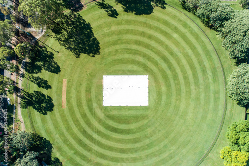Aerial view of a grassy cricket oval with covers over the wicket. photo