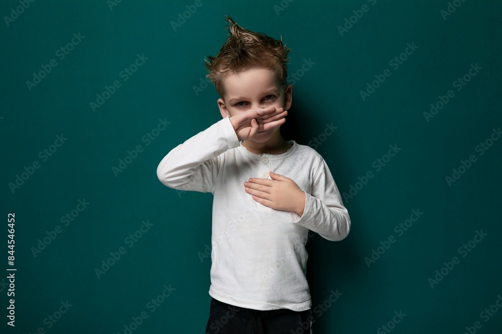 Little Boy Standing in Front of Green Wall