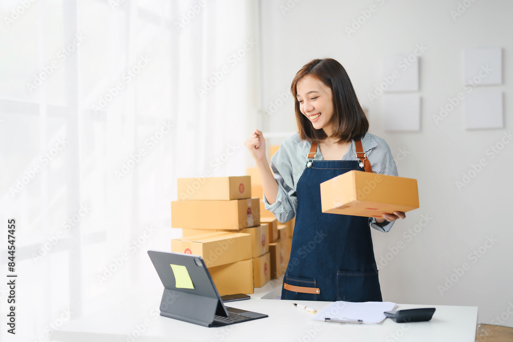 Young Woman Entrepreneur Working from Home, Packing Boxes for Online Orders, Celebrating Success, Small Business Owner, E-commerce, Home Office, Smiling, Happy, Product Shipping, Modern Workspace Young Woman Entrepreneur Working from Home, Packing Boxes for Online Orders, Celebrating Success, Small Business Owner, E-commerce, Home Office, Smiling, Happy, Product Shipping, Modern Workspace