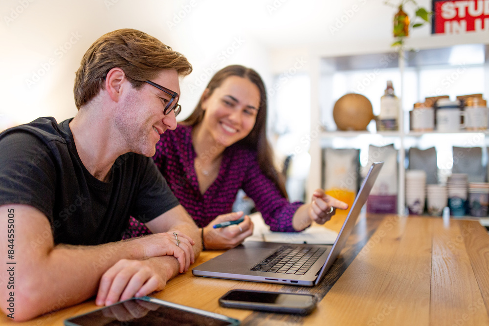 Two smiling businesspeople with a laptop discussing project Two smiling businesspeople with a laptop discussing project