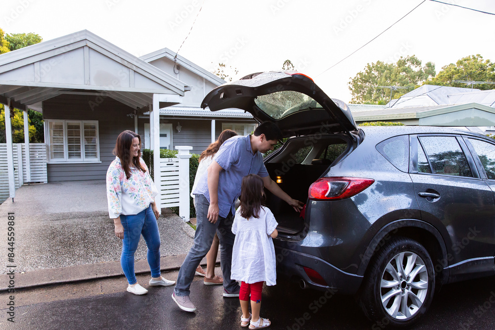 Two young girls helping dad get things loaded into boot of family car Two young girls helping dad get things loaded into boot of family car
