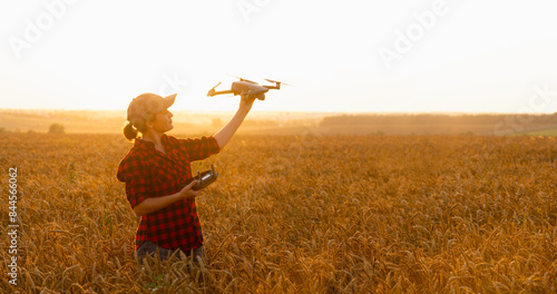 Woman farmer with drone on a wheat field. Smart farming and precision agriculture.