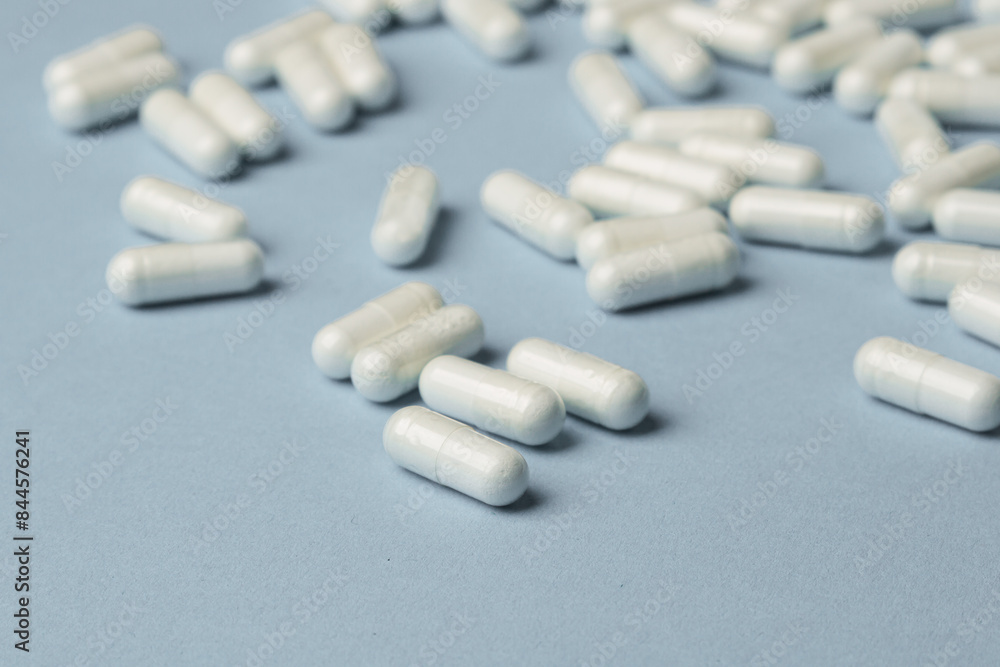 White capsules on a blue background. Vitamins and dietary supplements concept White capsules on a blue background. Vitamins and dietary supplements concept