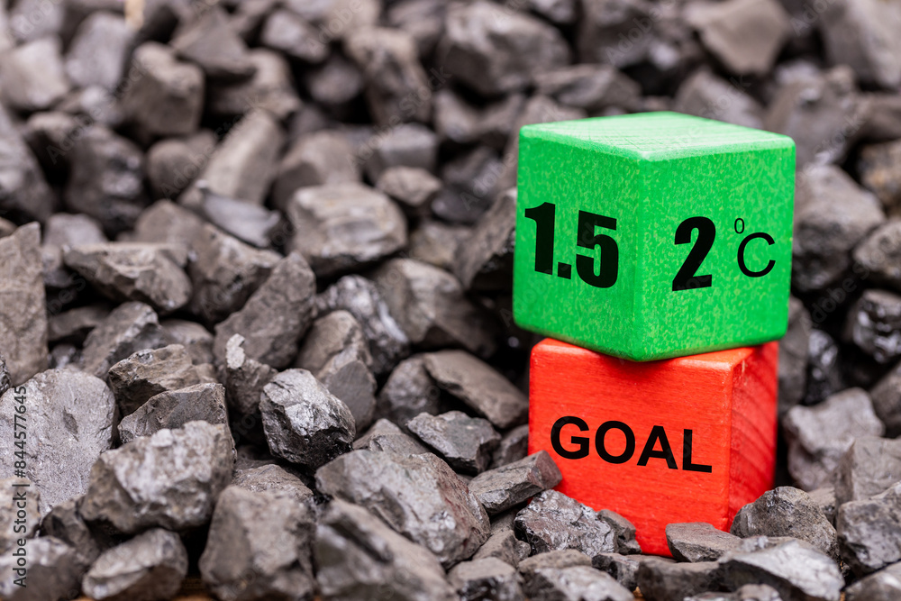 Symbol of reducing global warming among coal piles. A rotating wooden cube with the symbol