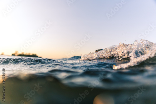 Surge of waves in orange sunset conditions close to water surface