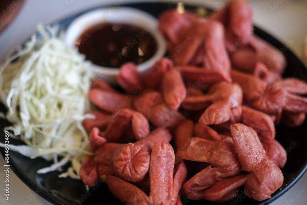 Red fried sausages with sweet dipping sauce on a plate with cabbage. It is a famous Thai street food Red fried sausages with sweet dipping sauce on a plate with cabbage. It is a famous Thai street food