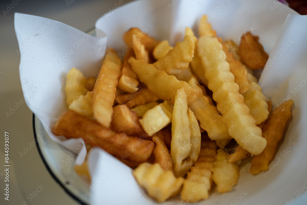 Close-up of French Fries served on paper in a bowl Close-up of French Fries served on paper in a bowl