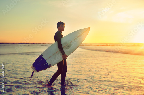 Photography Sunset, surf and teenager on beach with board for adventure on vacation, holiday or sport in water