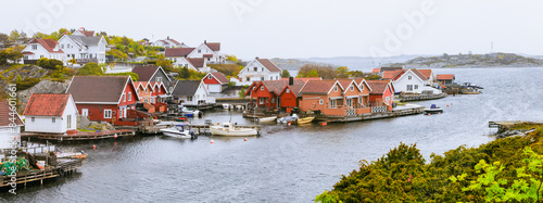 Charming Red and white cottages by the waterfront, with boats docked along the pier. Cold destinations travel trend. Kristiansand, Norway