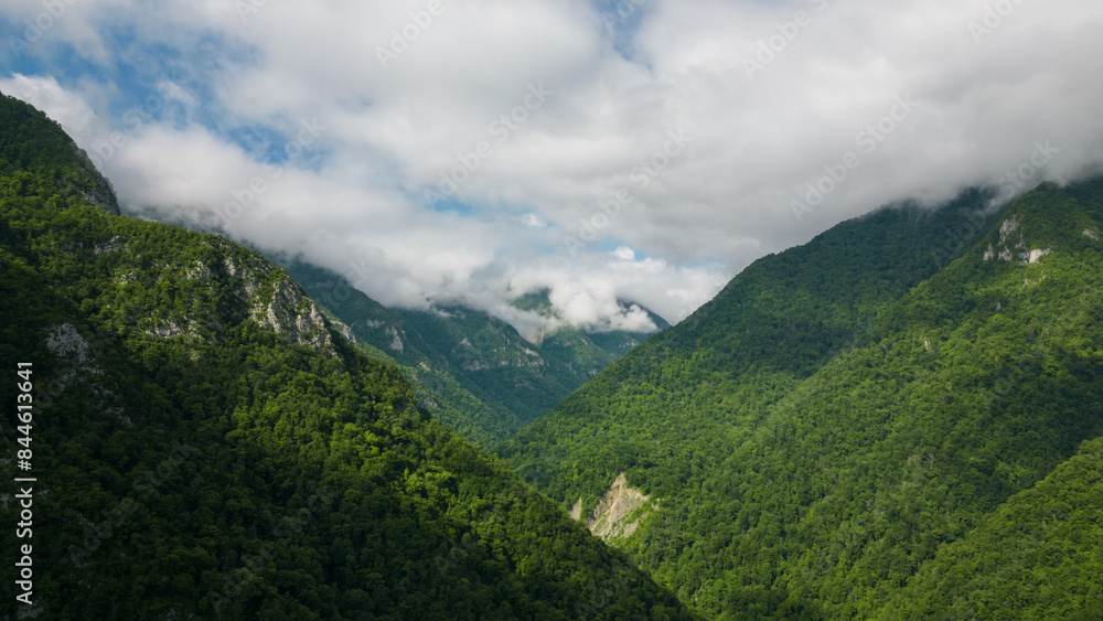 Obraz premium wonderful landscape of green mixed deciduous forest in the mountains and rocks against a background of beautiful clouds
