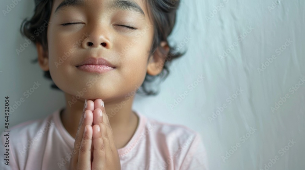 Young child with eyes closed hands clasped in prayer against a soft-focus background conveying a sense of peace and innocence. Young child with eyes closed hands clasped in prayer against a soft-focus background conveying a sense of peace and innocence.