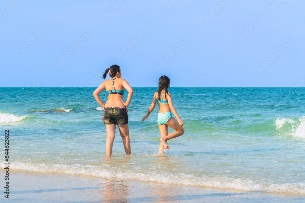 Mother and teenage daughter playing together on tropical beach at daytime. Mom and lovely daughter enjoy and fun outdoor lifestyle on beach. Happy family outdoors vacation. Friendly family Concept. Mother and teenage daughter playing together on tropical beach at daytime. Mom and lovely daughter enjoy and fun outdoor lifestyle on beach. Happy family outdoors vacation. Friendly family Concept.