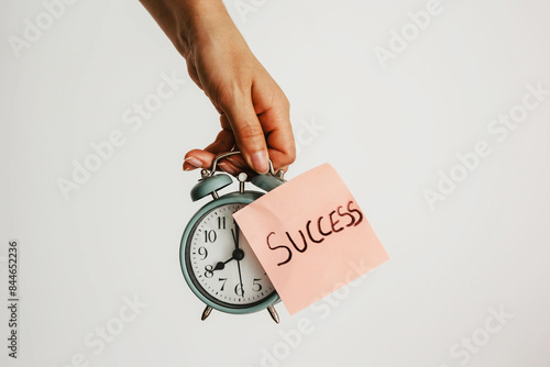 Schilderij op canvas Hand Holding Alarm Clock with Success Note – Time Management and Motivation Conc