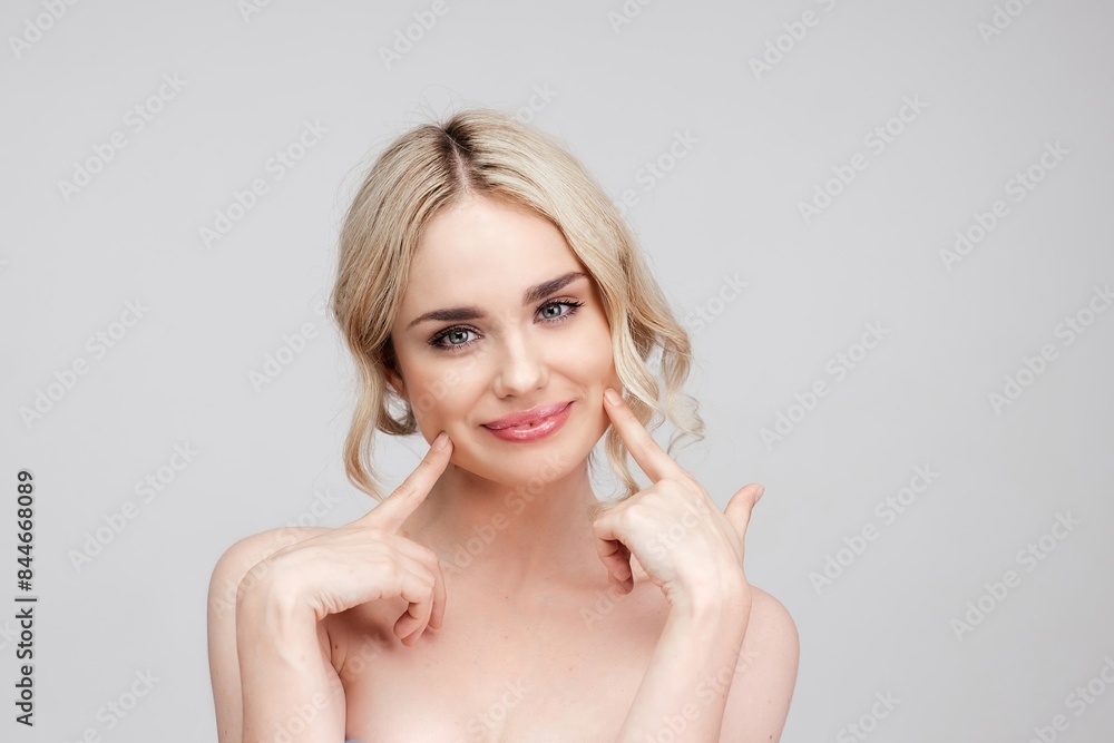 Naklejka premium High-quality portrait of skincare and cosmetics concept with copy space for text. Woman with beautiful face touching healthy facial skin. Beautiful smile with healthy white teeth, clear glowing skin. 