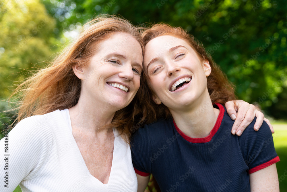 Happy Redhead Mother and Daughter Laughing Together in Park Happy Redhead Mother and Daughter Laughing Together in Park