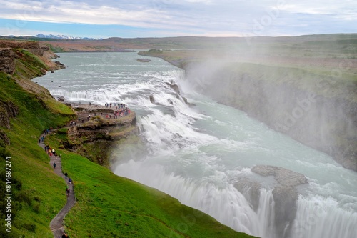 Tourists walking along the pat to view a wet Gullfoss waterfall
