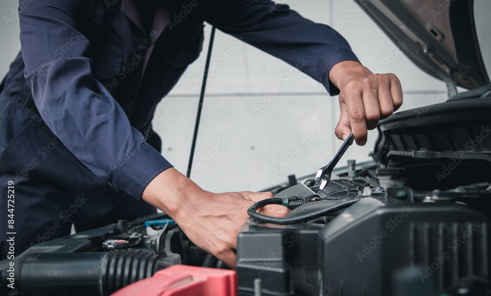 Mechanic using wrench while working on car engine outside the service center , Repair and service. Mechanic using wrench while working on car engine outside the service center , Repair and service.